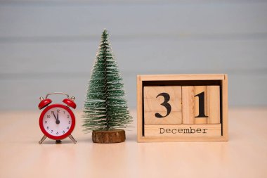 Yeni yıl ağacı ve mavi arka plan üzerinde kırmızı çalar saat ile ahşap takvimde 31 Aralık ayarla. Saati göster gece yarısına 5 dakika