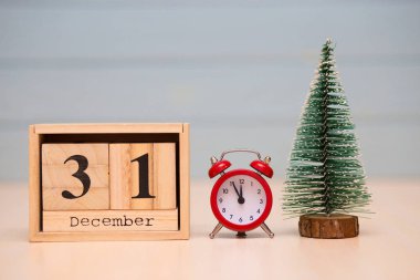 Yeni yıl ağacı ve mavi arka plan üzerinde kırmızı çalar saat ile ahşap takvimde 31 Aralık ayarla. Saati göster gece yarısına 5 dakika