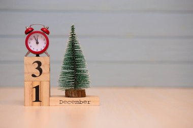 Yeni yıl ağacı ve mavi arka plan üzerinde kırmızı çalar saat ile ahşap takvimde 31 Aralık ayarla. Saati göster gece yarısına 5 dakika