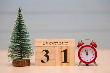 Yeni yıl ağacı ve mavi arka plan üzerinde kırmızı çalar saat ile ahşap takvimde 31 Aralık ayarla. Saati göster gece yarısına 5 dakika