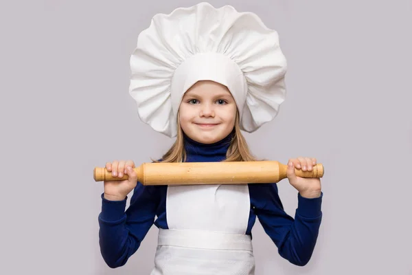 子供を調理します シェフの制服を着た幸せな少女は 麺棒は 白い背景で隔離を保持しています 子供のシェフ — ストック写真