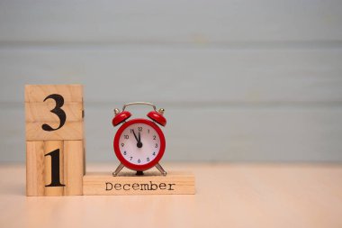 31 Aralık ahşap takvim ve mavi arka plan ile kırmızı alarm saati ayarlayın. Saati göster gece yarısına 5 dakika