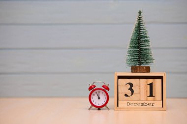 Yeni yıl ağacı ve mavi arka plan üzerinde kırmızı çalar saat ile ahşap takvimde 31 Aralık ayarla. Saati göster gece yarısına 5 dakika