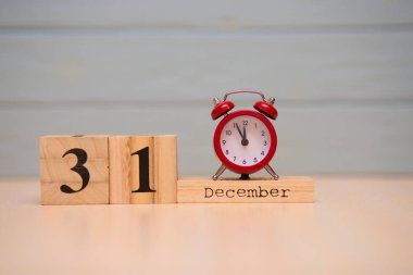 31 Aralık ahşap takvim ve mavi arka plan ile kırmızı alarm saati ayarlayın. Saati göster gece yarısına 5 dakika