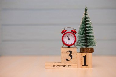 Yeni yıl ağacı ve mavi arka plan üzerinde kırmızı çalar saat ile ahşap takvimde 31 Aralık ayarla. Saati göster gece yarısına 5 dakika