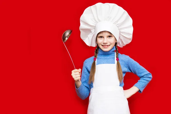 シェフの制服を着た幸せな少女は 赤に分離されたスプーンを保持しています 子供のシェフ 調理プロセスの概念 — ストック写真