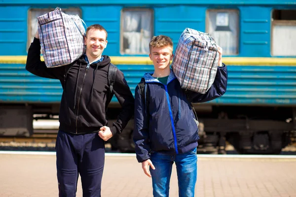 Два человека с большими сумками на вокзале. Путешествие на поезде — стоковое фото