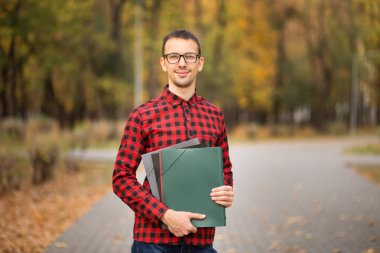Takım lideri klasörlerle bardaklarda ofise sonbahar park ile gitmek