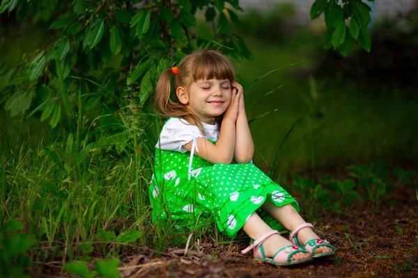 日当たりの良い夏の日に庭で緑の草の上に座って女の子 — ストック写真