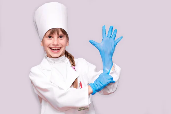 医療制服と青用手袋白で隔離カメラ目線の笑顔の少女 — ストック写真