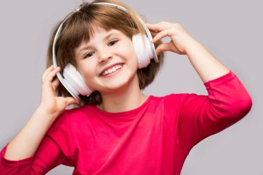 Mutlu gülümseyen çocuk kulaklık müzik dinler beyaz arka plan üzerinde sahiptir.