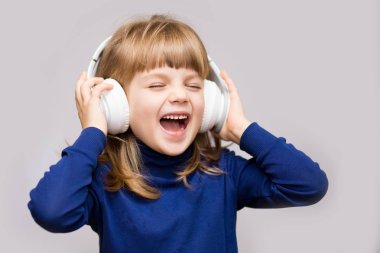 Kapalı gözler Studio beyaz arka plan ile müzik dinlerken kulaklık ile enerji çocuk kız.