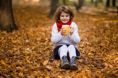 Mutlu küçük kız surround sarı sonbahar Park'ta sıcak çay içecekler