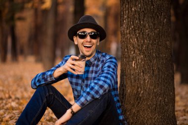 Yakışıklı adam kağıt bardak sonbahar Park'ta yürüyordunuz sabah kahve ile sakallı