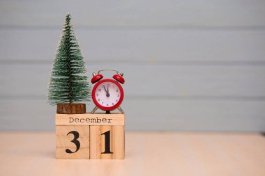Yeni yıl ağacı ve mavi arka plan üzerinde kırmızı çalar saat ile ahşap takvimde 31 Aralık ayarla. Saati göster gece yarısına 5 dakika