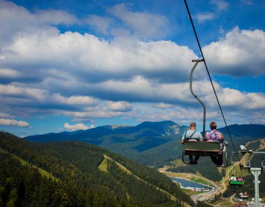 Yaz aylarında Chairlift oturan insanlar dağlarda yürüyüş