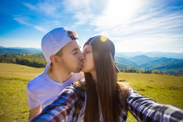 Young couple hiking taking selfie with smart phone. Happy young man and woman taking self portrait with mountain scenery background