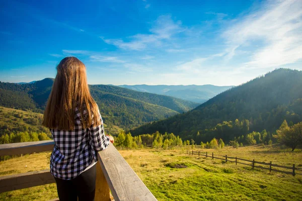 Slim pleasant woman on wooden balcony rejoicing wonderful view of Carpathian mountains