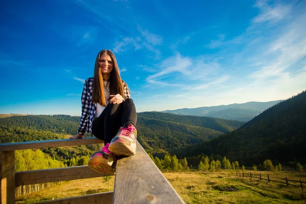 Slim pleasant woman on wooden balcony rejoicing wonderful view of Carpathian mountains