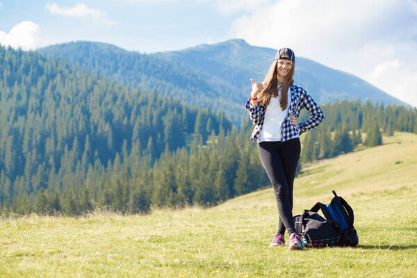Young happy tourist woman with backpack on top of mountains contemplating beautiful view and enjoy freedom