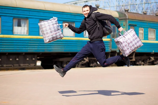 Young man with big bags at railway station. Travel by train