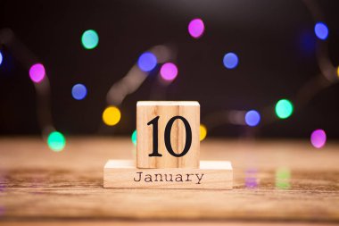 10 Ocak. Garland bokeh ile koyu arka plan üzerinde ahşap takviminde gün 10 Ocak ayarlayın. Kış saati.