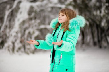 Sevimli küçük kız uzanır yakalamak için elini düşen kar taneleri. İlk kar