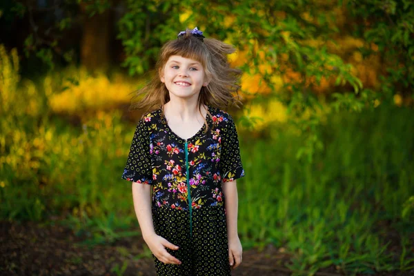 夕暮れ時の公園を歩いて愛らしい笑みを浮かべて少女の肖像画 — ストック写真