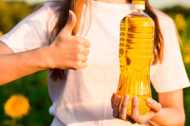 Beyaz holding şişe yağı ayçiçeği alanında genç kadın