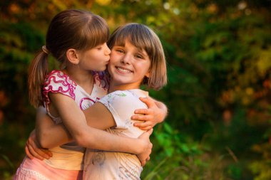 İki sevimli küçük gülüyor ve güneşli günde yaz parkta sarılma kız