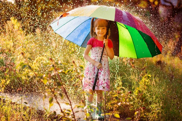 Mutlu çocuk kız yürümek Sonbahar yağmur altında çok renkli şemsiye ile