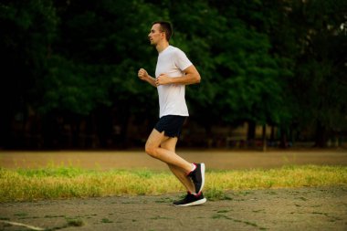 Doğa akşamları koşan atletik genç adam.