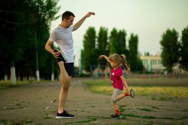 Atletik genç baba ve küçük kızı stadyumda egzersizleri yapın. Sağlıklı yaşam tarzı