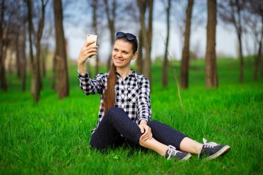 Parkta dinlenmiş ve telefonda selfie çeken güzel bir kadın. İletişim ve boş zaman kavramı