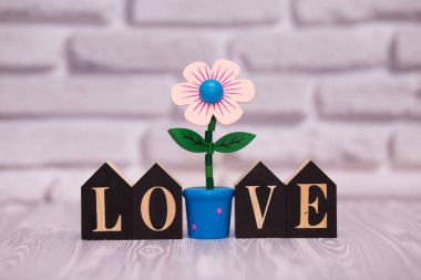 Metin güzel oyuncak çiçek beyaz tuğla zemin üzerine siyah ahşap bloklar üzerinde seviyorum.