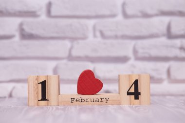 14 Şubat beyaz tuğla zemin üzerine kırmızı kalpli ahşap Takvimi ayarla.