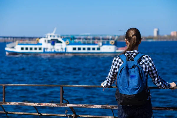 Arkadan görünüşü turist kadın sırt çantası ayakta ile deniz kenarında iskelede güneşli bahar gününde