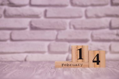 Beyaz tuğla arka plan ile ahşap takvim üzerinde 14 Şubat ayarla.