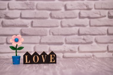 Metin güzel oyuncak çiçek beyaz tuğla zemin üzerine siyah ahşap bloklar üzerinde seviyorum.