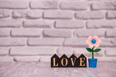Metin güzel oyuncak çiçek beyaz tuğla zemin üzerine siyah ahşap bloklar üzerinde seviyorum.