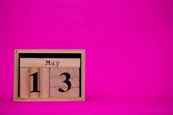 May 13th. Day 13 of may month set on wooden calendar isolated on pink background. Spring time. Empty space for text, mockup.