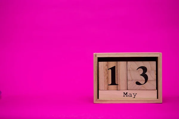 May 13th. Day 13 of may month set on wooden calendar isolated on pink background. Spring time. Empty space for text, mockup.