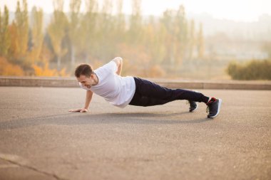 Açık havada yukarı itin yapan genç atletik erkek. Atletik bir adam. Adam doğa sporları yapan. Spor hayatı.