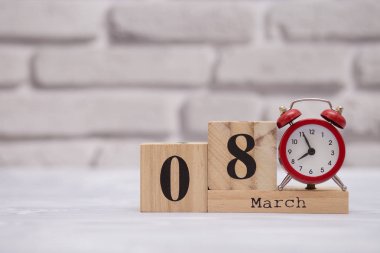 Mart 8. Beyaz tuğla zemin üzerine kırmızı alarm saatli ahşap takviminde ayın günü 8. Kadınlar günün kutlu olsun.