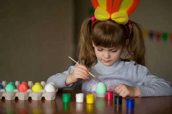 Счастливая девушка с кроличьими ушами, рисующая яйца кистью. — стоковое фото