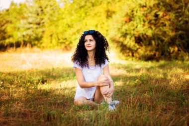 Çok kıvırcık kadınla çimenlerin üzerinde güneşli bir günde poz