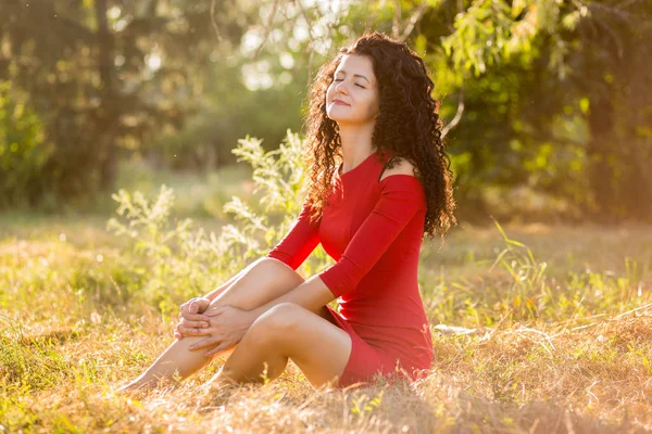 Gelukkig mooie jonge vrouw in rode jurk kunt u ontspannen in de zomer park. Vrijheid en harmonie concept — Stockfoto
