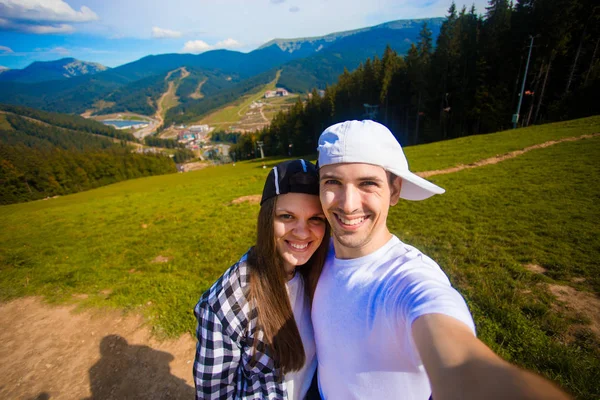 Young couple hiking taking selfie with smart phone. Happy young man and woman taking self portrait with mountain scenery