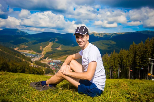 Человек турист расслабляясь на вершине холма и любуясь красивым видом на горную долину летом — стоковое фото