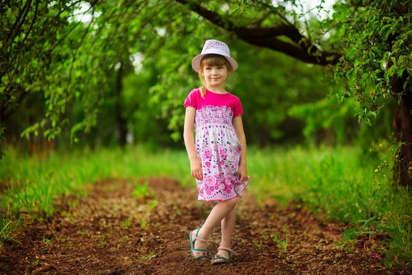 Happy little girl in bright dress walk in garden — Stock Photo, Image